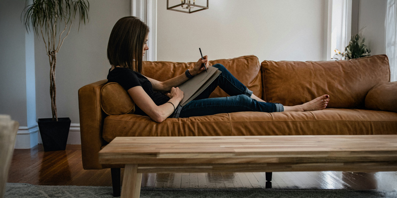Frau sitzt auf dem Sofa und zeichnet