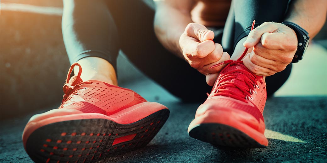 Frau bindet sich Sportschuhe zu